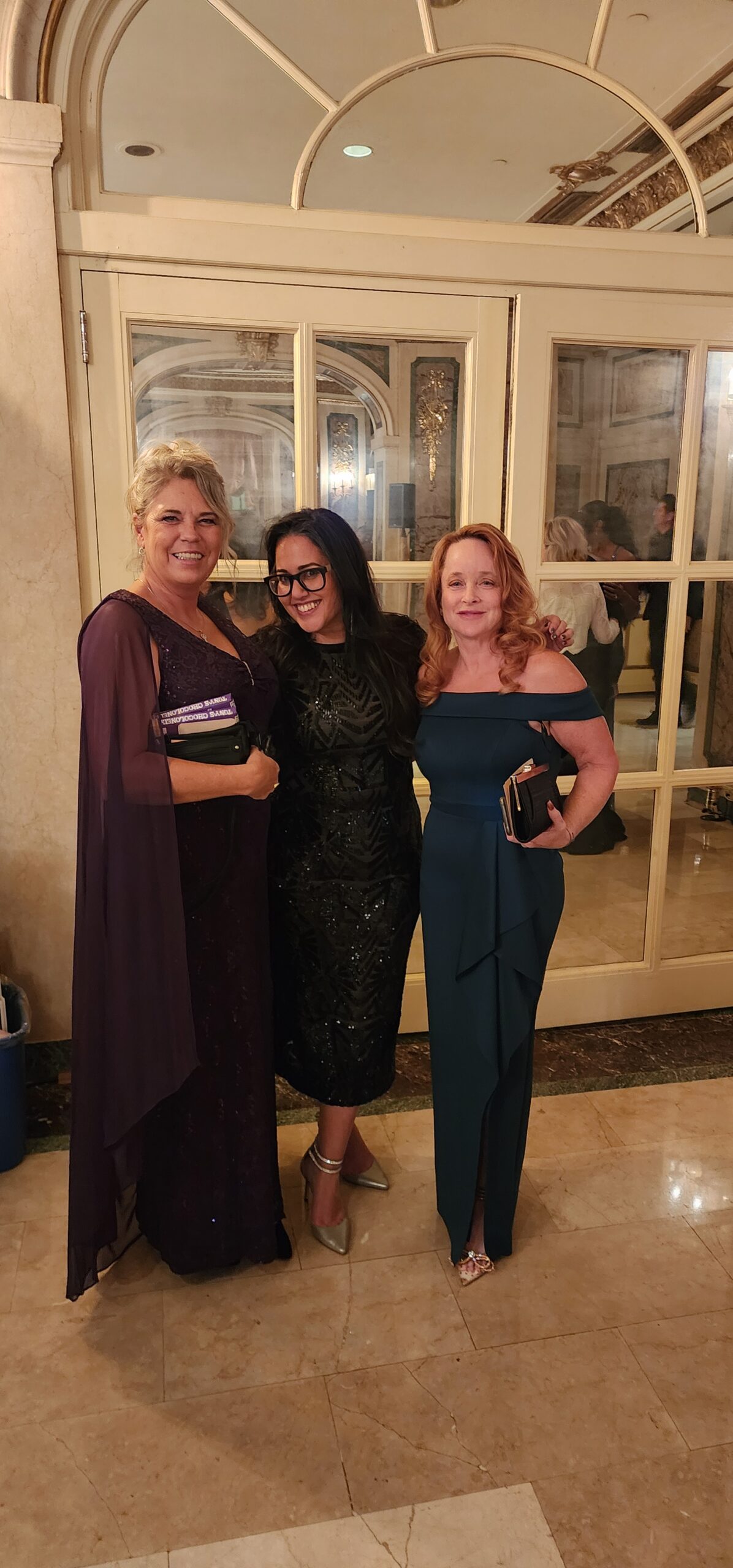 Three Women in Elegant Formal Dresses Pose Together
