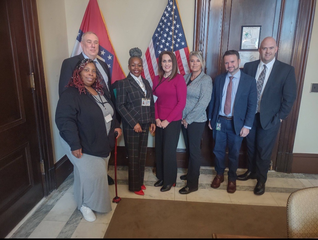 A diverse group of individuals stands proudly in front of a large flag, showcasing unity and patriotism.